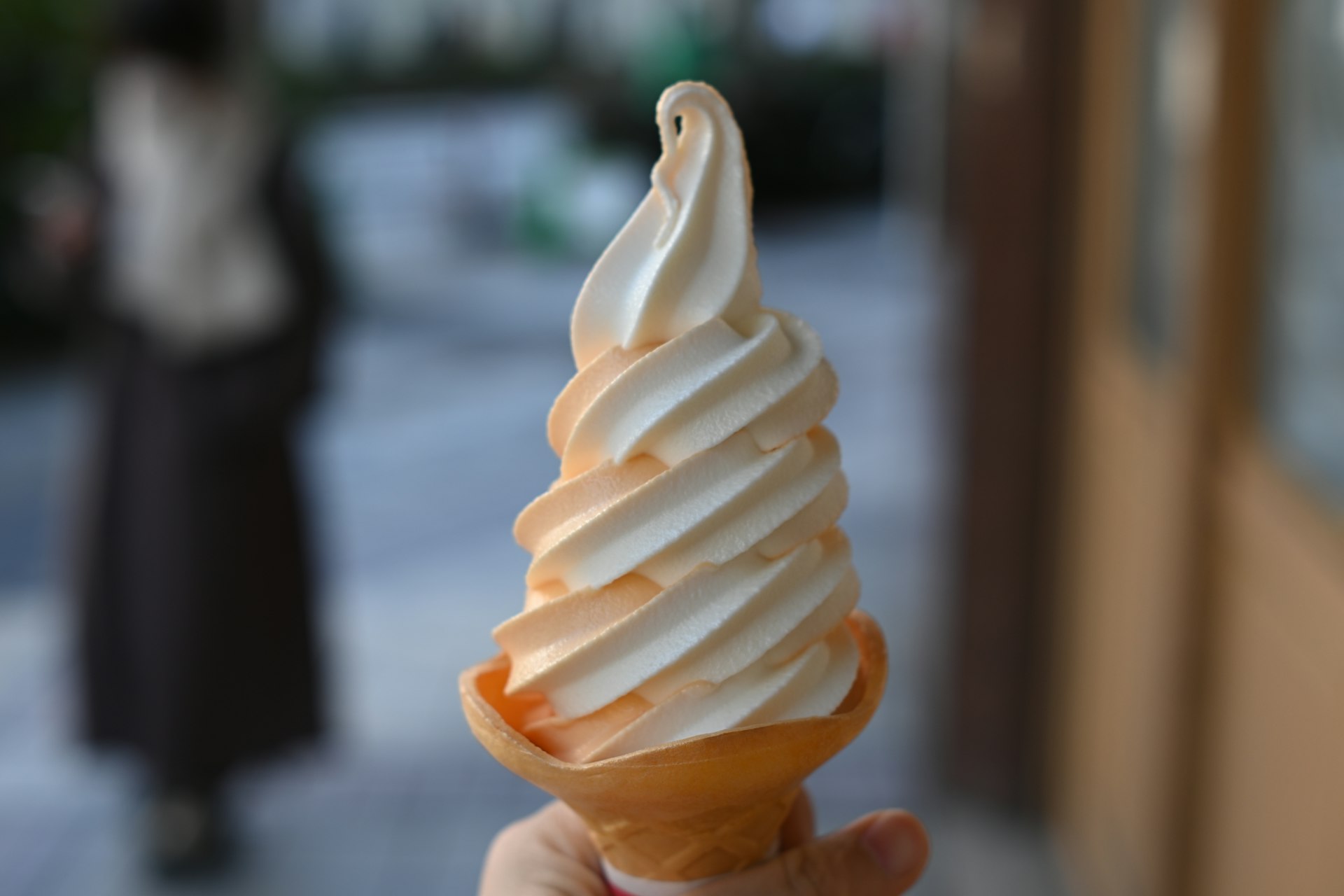 a hand holding an ice cream cone on a city street